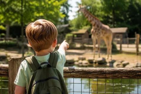 Kinderen kijken naar giraffen en zebras op de savanne van Van Blanckendaell Park