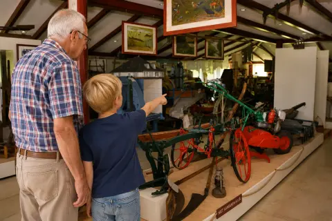 Opa en kleinkind bekijken oude werktuigen in Museum Historisch Harenkarspel