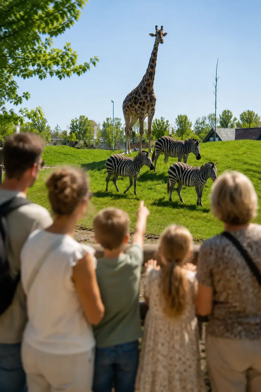kinderen kijken naar de giraffen en zebra's op de Savanne bij Van Blanckendaell Park